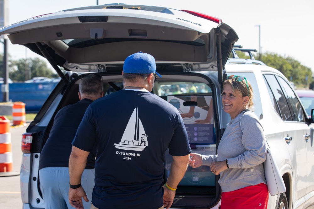 GVSU Mom smiles at GVSU Alumnus as he helps unload family's car